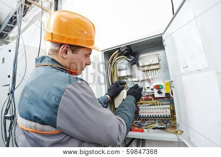 Young adult electrician builder engineer screwing equipment in fuse box