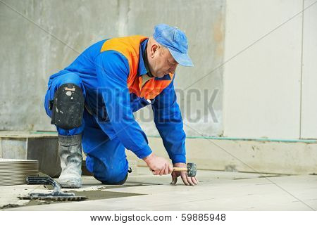 Two industrial tiler builder worker installing floor tile at repair renovation work