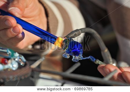 TEL AVIV, ISRAEL - FEBRUARY 11, 2012: Delicate work of the glass blower. The Artist-glass blower produces a graceful tiny figure of an elephant from color glass. 