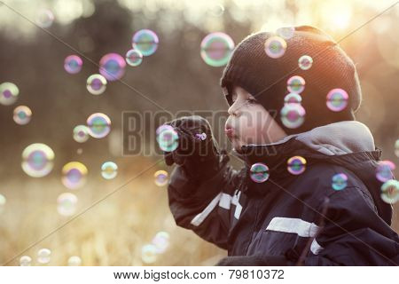 Little boy playing with bubble wand blowing soap bubbles