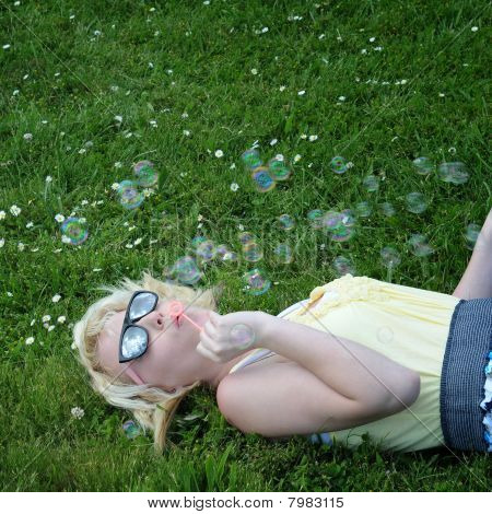Flicka blåsa bubblor i gräs