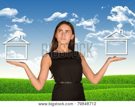 Businesswoman holding two houses as if chosing