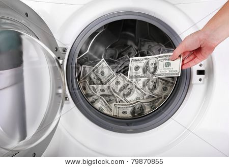 Female putting money into washing machine, closeup