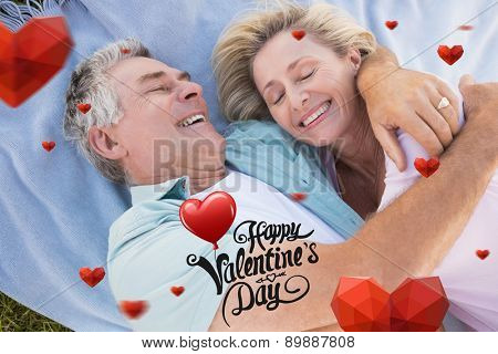 Happy senior couple cuddling on blanket against cute valentines message