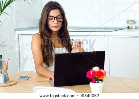 Beautiful Young Woman Using Her Laptop Amb Drinking Coffee At Home.