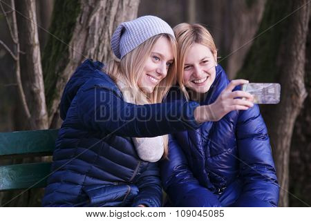 Young woman sitting on bench with her best friend