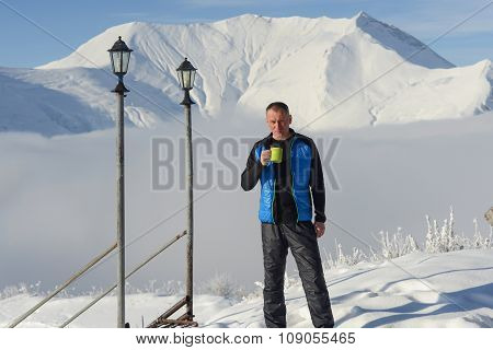 Man Relaxing Standing With Cup Of Coffee On The Background Of Snow-capped mountains