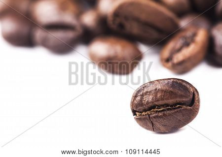 Rosted brown coffee beans lying on white background, selective focus