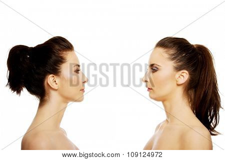 Two attractive sisters standing face to face.