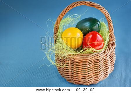 Easter Eggs Painted with red, yellow colors and green in the Basket on the woden table
