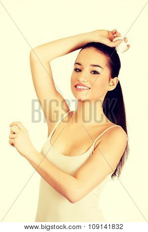 Young smiling woman applying anti perspirant.