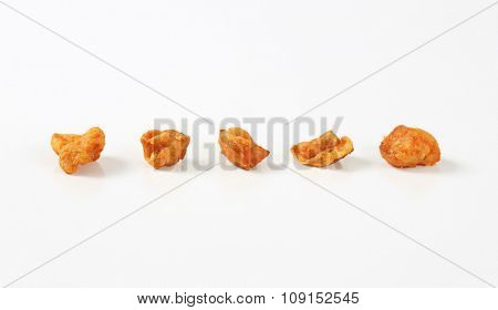 five pork greaves in a row on white background
