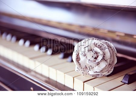 Vintage old classic piano with paper rose and musical notes on it, close up
