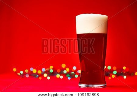Full glass of bear or ale with blurred christmas lights in background