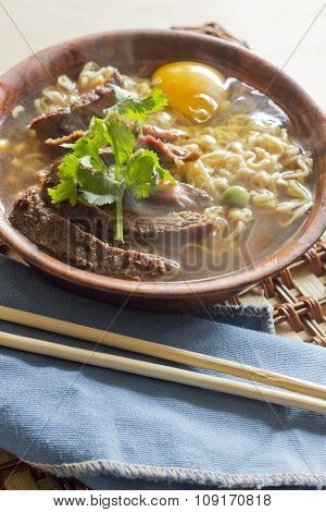 Beef ramen served Asian style. Raw egg cooks in steaming hot savory broth