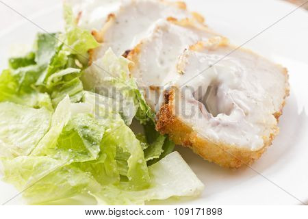 Sliced chicken cordon bleu with creamy sauce and romane leaf salad