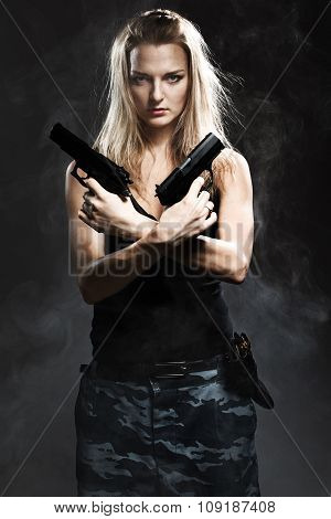 Sexy woman holding gun with smoke. studio shot