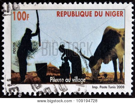 NIGER - CIRCA 2008: A stamp printed in Niger shows pileuse au village circa 2008