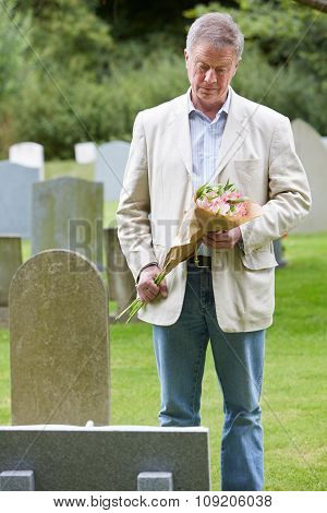 Man Laying Flowers On Grave