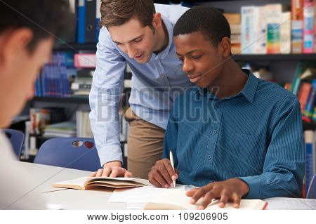 Teacher Helping Male Student In Classroom
