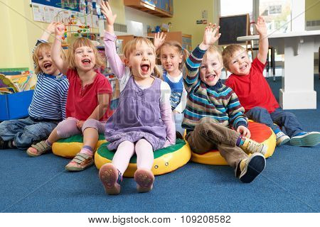 Group Of Pre School Children Answering Question In Classroom