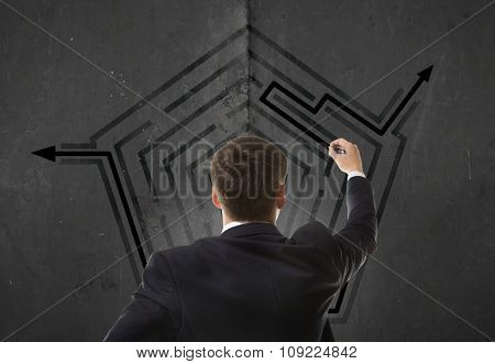Business concept. Back view of businessman looking at a maze on wall