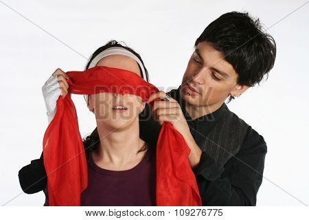 Man putting red blindfold on woman eyes. Happy love couple game