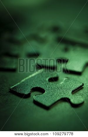 Green jigsaw parts on dark background. Puzzle concept