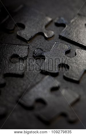 Black jigsaw parts on dark background. Puzzle concept