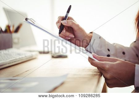 Cropped image of woman writing on clipboard in her office