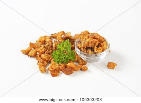 bowl of salty pork greaves on white background