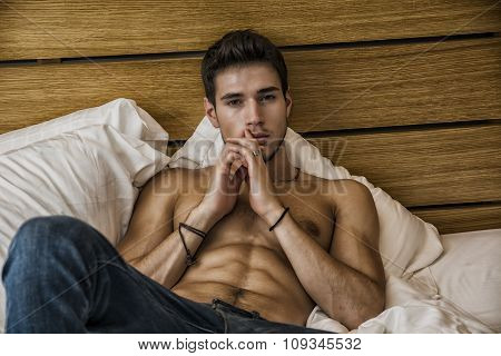 Shirtless sexy male model lying alone on his bed