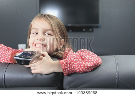 cute little girl with remote control in front of TV.