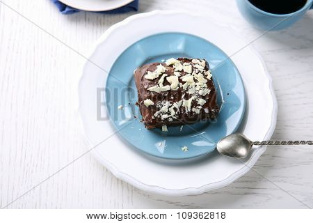 Delicious chocolate brownie on plate on wooden background