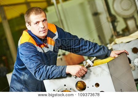 Portrait of industrial worker assembling the reduction gear box on production line manufacturing workshop