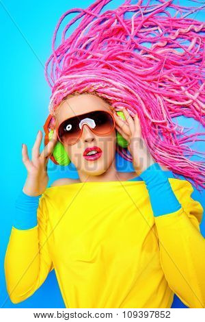 Ultra trendy DJ party girl in bright clothes, headphones and with bright dreadlocks. Disco, party. Show business. Bright fashion.