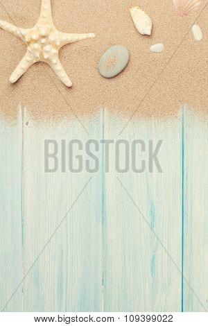 Sea sand with starfish and shells on wooden table. Top view with copy space. Toned