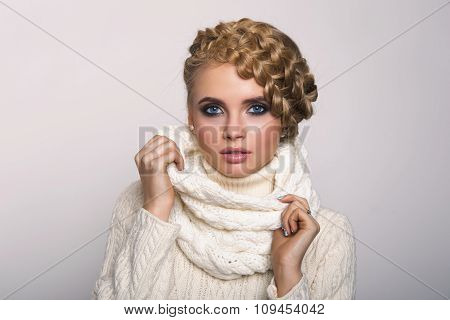 portrait of a beautiful young blonde woman on a light background. hair tied in a braid. girl wearing