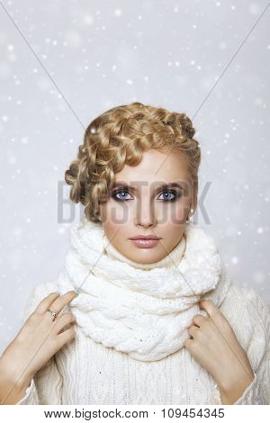 portrait of a beautiful young blonde woman on a light background. hair tied in a braid. girl wearing