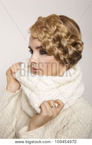 portrait of a beautiful young blonde woman on a light background. hair tied in a braid. girl wearing