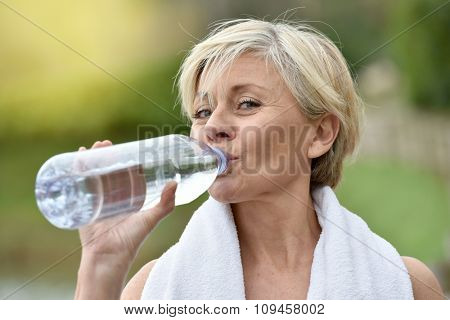 Senior woman drinking water after exercising