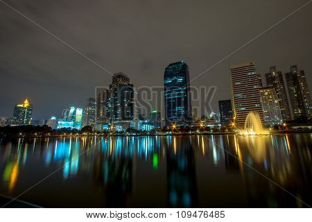Golden reflection light in lake and Night view of Bangkok downtown at Benja kitti park, Thailand.