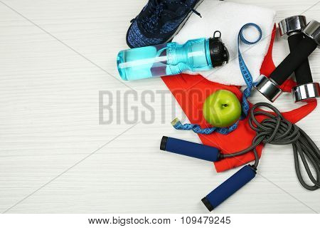 Sport clothes, shoes and sport equipment on light background