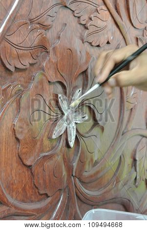 Skilled craftsman adding gold leaf skin to the wood carving