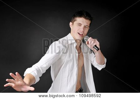 Expressively Man Singing With Microphone On Dark Background.