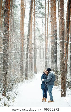 Young Couple Embracing In Winter Forest