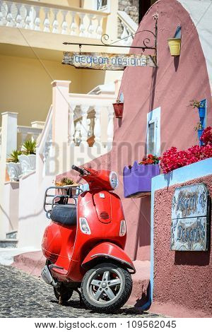 Red motor scooter as a part of decoration at color street of Thira town
