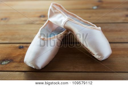 ballet, footwear and objects concept - close up of pointe shoes on wooden floor