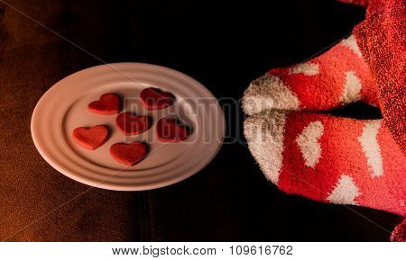 Feet in socks with hearts and cookies in shape of heart