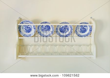 Plates on the shelf in white kitchen.